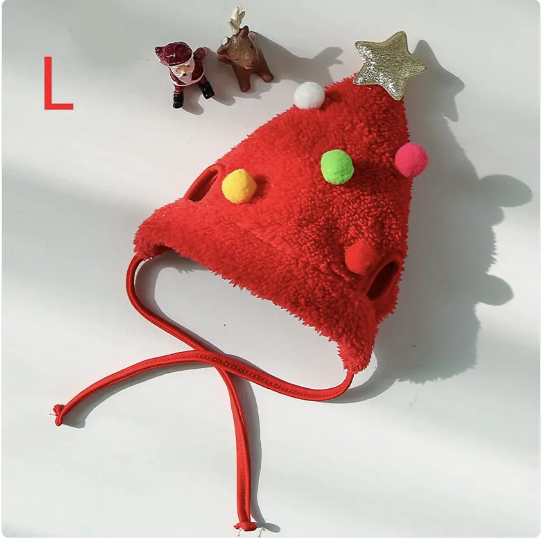 Red fuzzy Santa pet hat with colorful pom-poms and a star on a white background